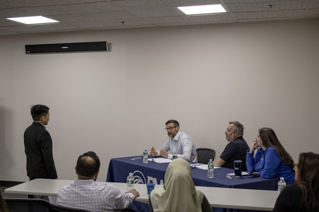 Mahdi Naqvi speaking with Paul K. Boyce, Jim Rhodes and Jennifer Lewis of PWGC